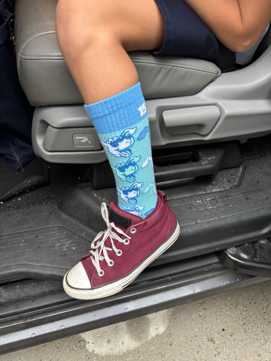 Close-up of a kid in a car wearing Rovertown socks with burgundy Converse sneakers